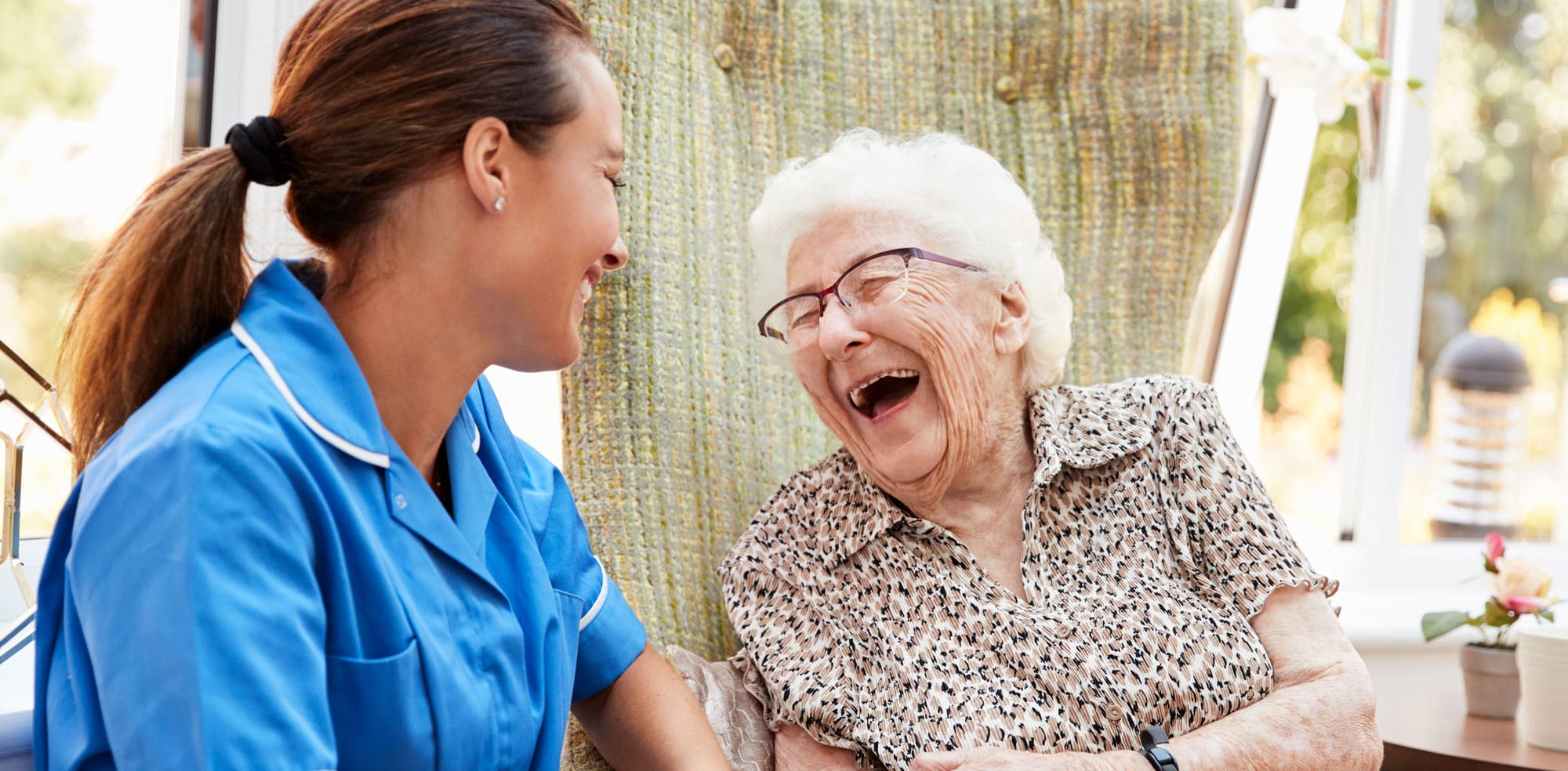 Older woman laughing with caregiver